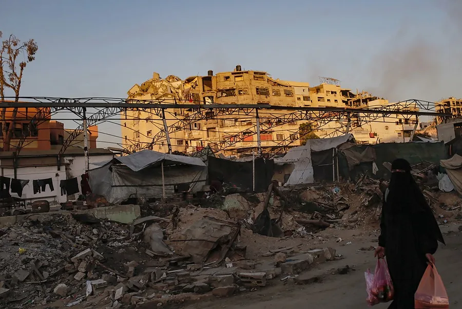 Una mujer palestina camina por una calle junto a edificios dañados durante una operación militar israelí en la ciudad de Gaza, Franja de Gaza.