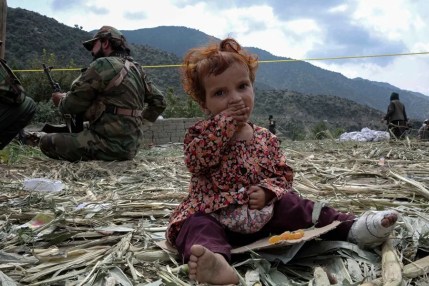 Un niño herido, víctima del terremoto, se sienta junto a agentes de seguridad en Kunar,
