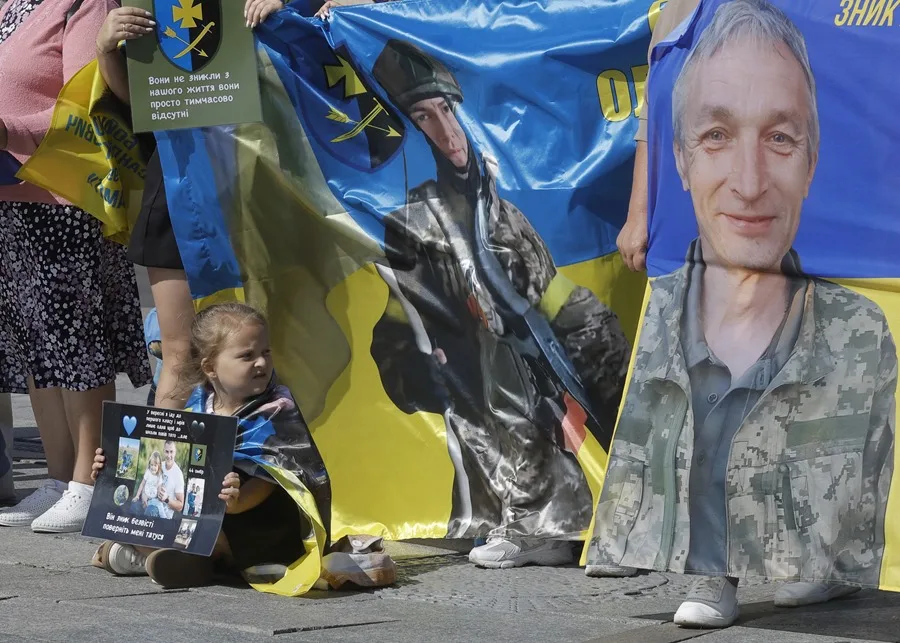La pequeña Elvira (6 años) sostiene una pancarta con la petición de encontrar a su padre durante una acción en apoyo a los prisioneros de guerra y las personas desaparecidas en la Plaza de la Independencia