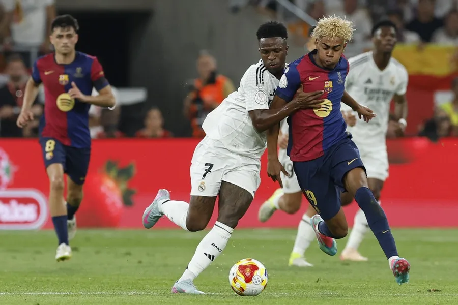 El delantero brasileño del Real Madrid Vinicius Jr. (i) lucha con Lamine Yamal, del FC Barcelona
