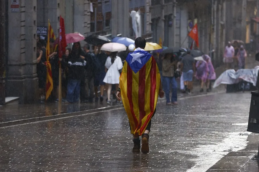 Una joven con una estelada camina bajo la lluvia este jueves en Barcelona.