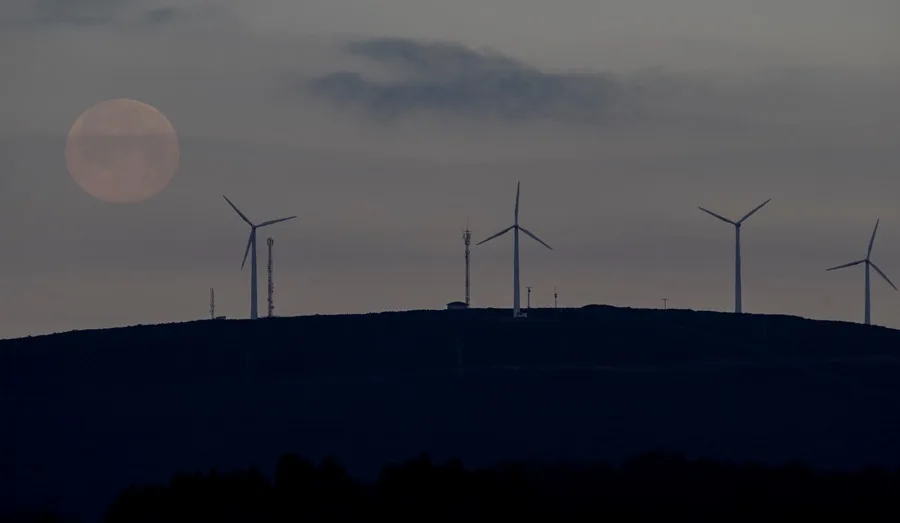 La primera luna llena de 2022, conocida como luna del lobo, vista sobre varios molinos de viento en Palas de Rei, Lugo. 