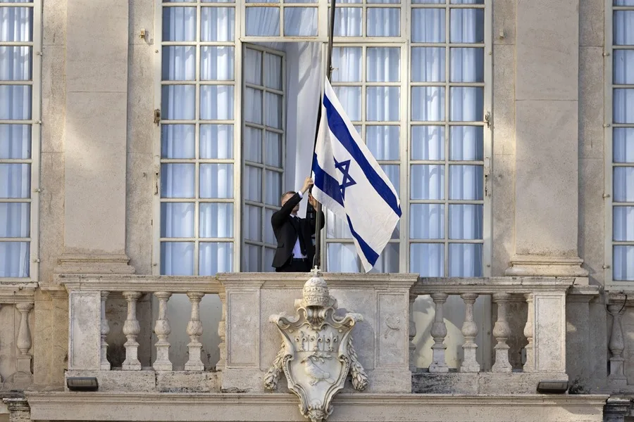 Un miembro de seguridad ajusta la bandera israelí antes de la llegada del presidente israelí para reunirse con el Papa León XIV en el Vatican
