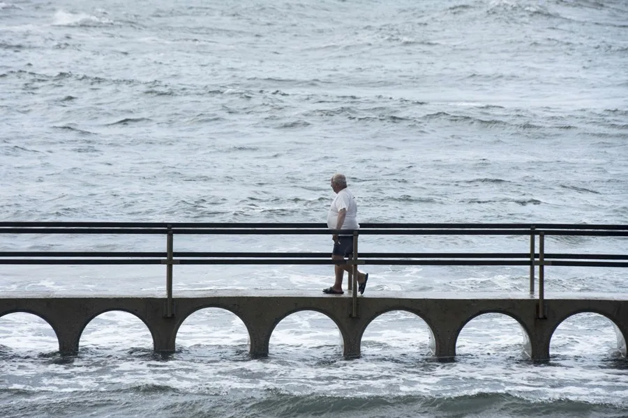 Un hombre cruza este domingo por la pasarela de Sa Mesquida en el litoral norte de Menorca donde rompe el fuerte viento de tramontana. El temporal de lluvia y fuertes vientos ha dejado hasta las 16:00 horas de este domingo un total de 260 incidencias en Baleares.