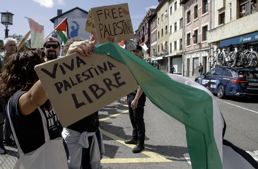 Decenas de personas con banderas de Palestina condenan el genocidio en Gaza durante la etapa 13 de la Vuelta Ciclista a España 2025.