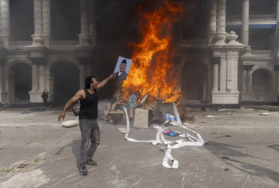 Un manifestante se prepara para quemar una imagen del dimitido primer ministro K.P. Sharma Oli mientras asalta el palacio Singha Durbar,