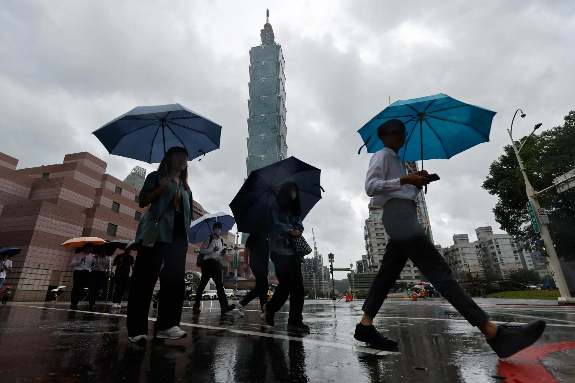 People sheltering under umbrellas cross the street near the Taipei 101 skyscraper building during the afternoon in the wake of Typhoon Ragasa in Taipei, Taiwan, 23 September 2025. EFE-EPA/RITCHIE B. TONGO