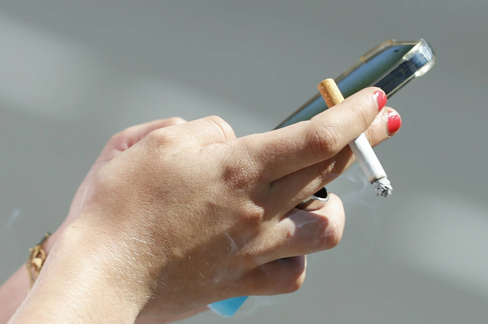 Foto de archivo de una mujer fumando un cigarrillo mientras consulta el móvil. EFE/ J.J.Guillen