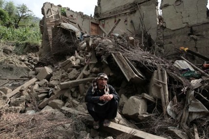 Una víctima del terremoto se sienta junto a los escombros de una casa dañada en Kunar