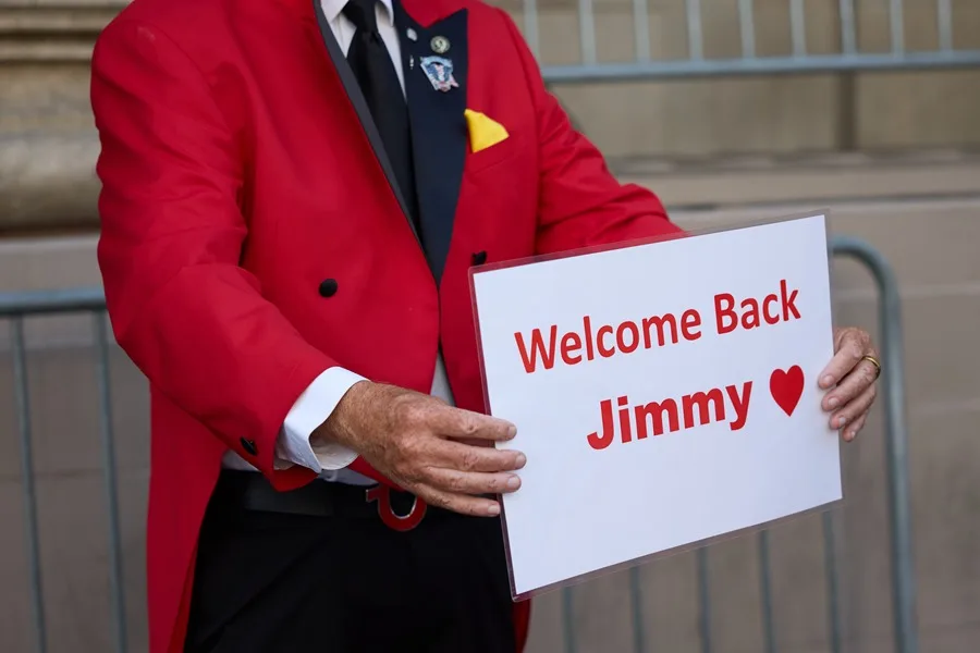 El actor Gregg Donovan sostiene un cartel dando la bienvenida a Jimmy Kimmel en Los Ángeles