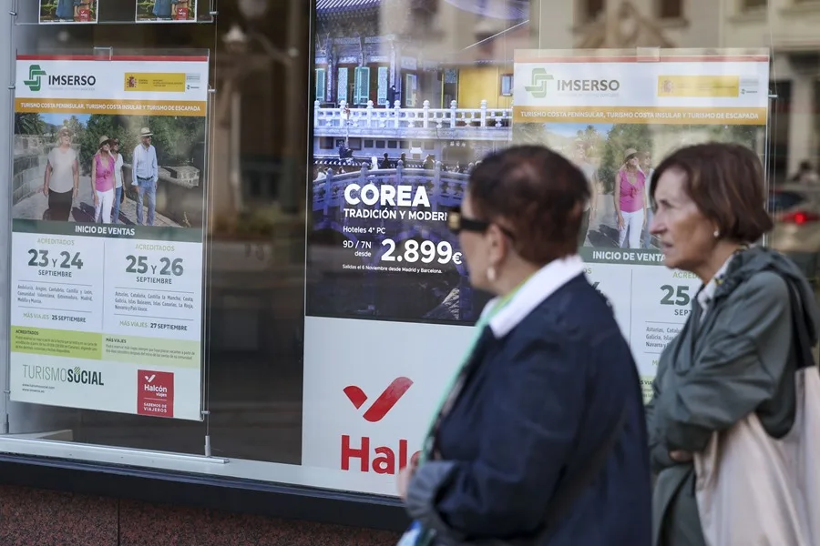 Dos jubiladas pasan por delante de una agencia de viajes donde anuncia viajes del Imserso. 