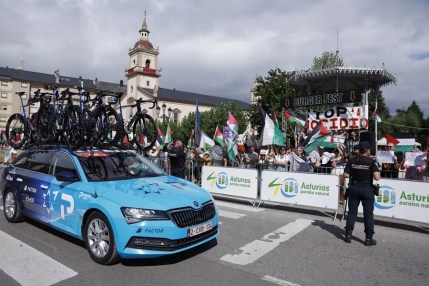 El coche del equipo Israel-Tech pasa delante los manifestantes que muestran su apoyo a Palestina