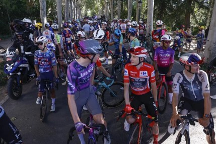 Jonas Vingegaard (2D), del equipo Visma, y ​​el pelotón esperan a unos 57 kilómetros de la meta debido a las protestas de Propalestina