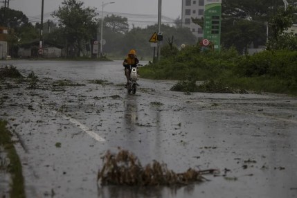 Una persona conduce una motoneta por una carretera cubierta de escombros durante el paso del tifón