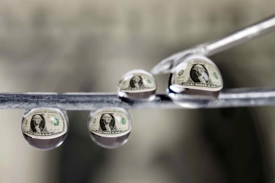 Billetes de un dólar reflejados en gotas de agua en San José (Costa Rica).