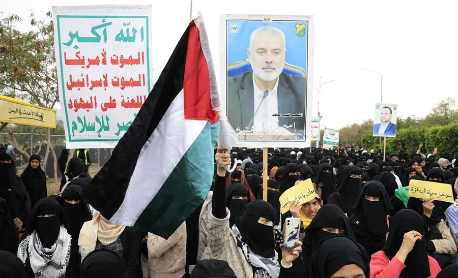 Un manifestante ondea una bandera palestina mientras otro sostiene una pancarta con la imagen del difunto líder de Hamás, Ismail Haniyeh