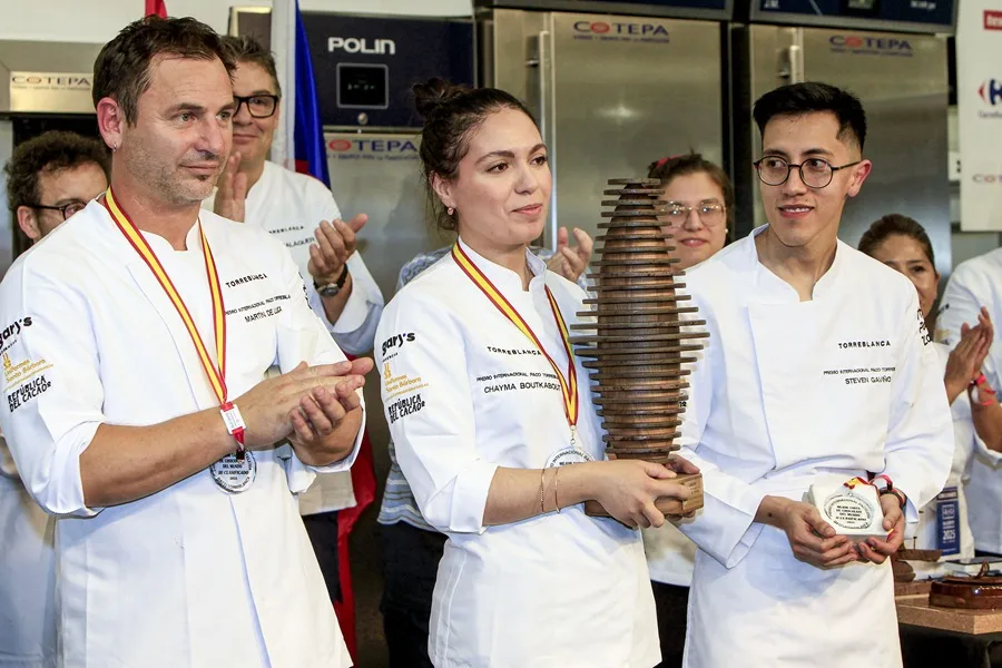 La ganadora a mejor tarta de chocolate del mundo, la repostera marroquí Chayma Boutkabout junto a los finalistas, el ecuatoriano Steben Gaviño (d), y hispanoargentino Martín de Luca (i).