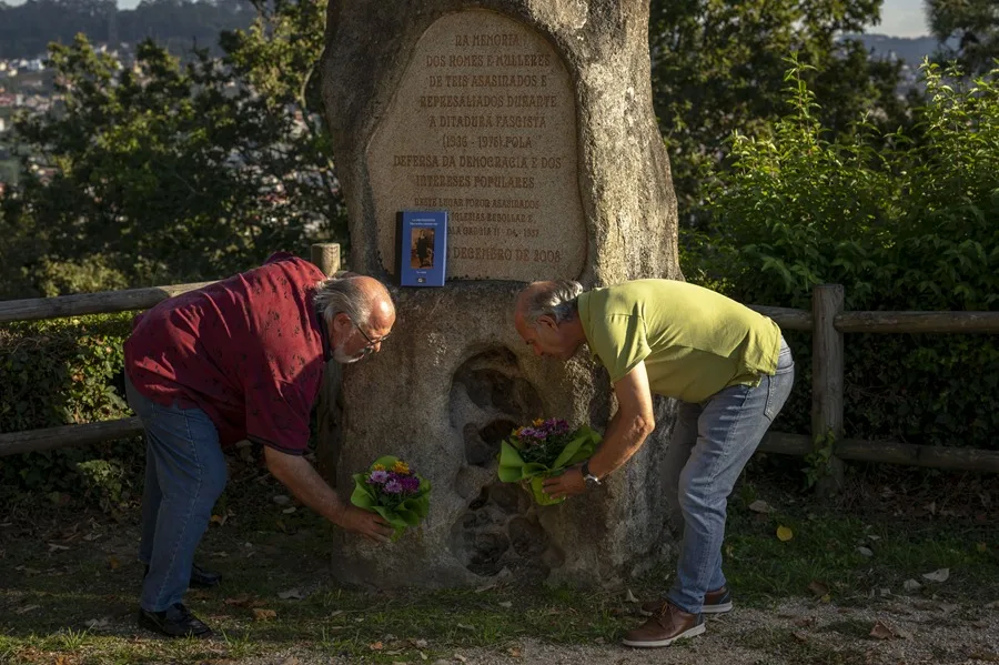 El periodista Paco Niebla y su hermano colocan flores junto al monolito dedicado a sus abuelos y a los represaliados durante la Guerra Civil, en el Monte da Guía.