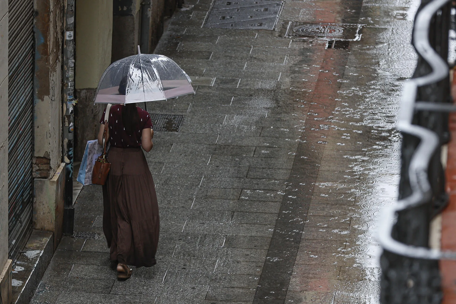 En la imagen de archivo, una persona camina bajo la lluvia en una calle de Valencia. EFE/Manuel Bruque
