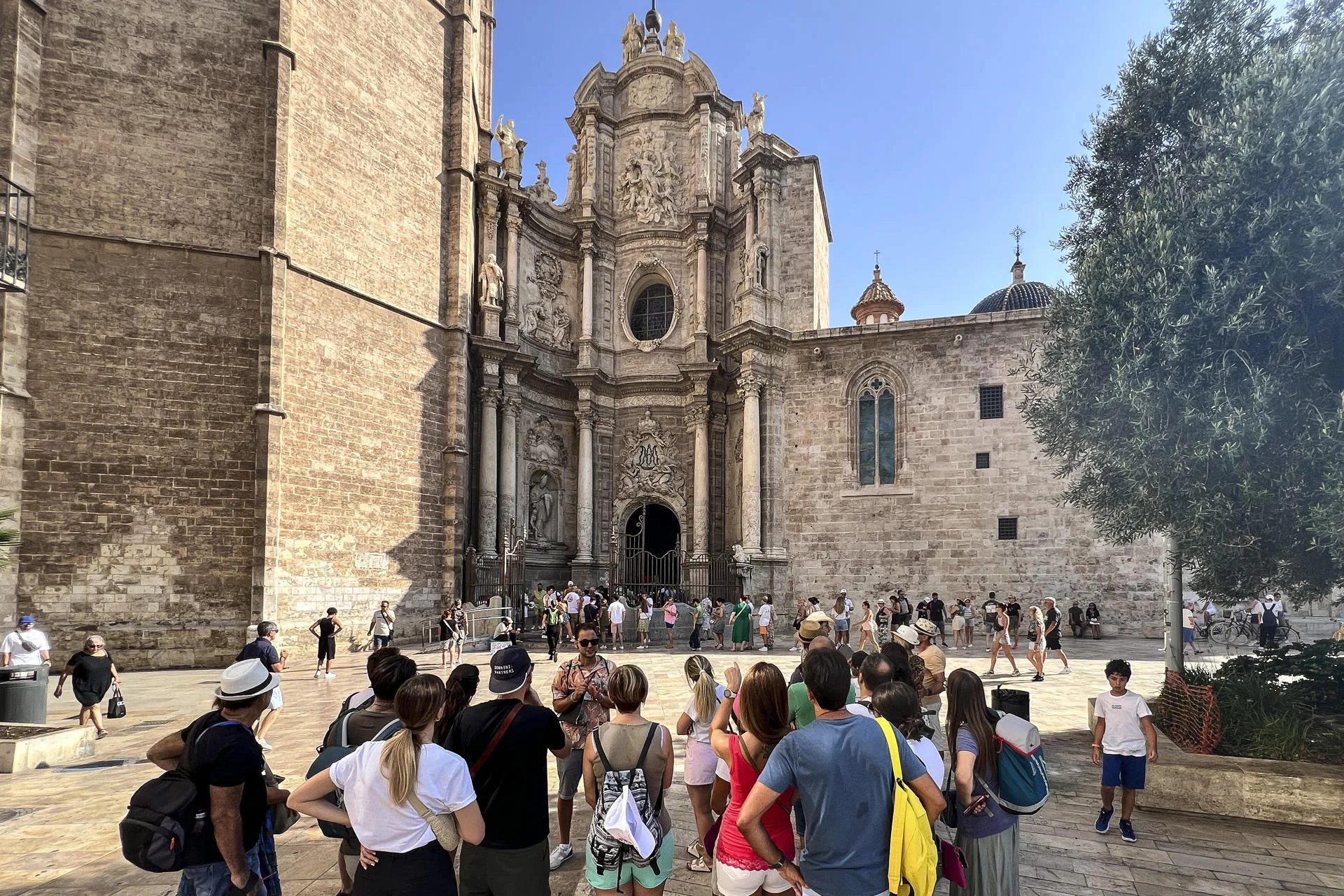 Un grupo de turistas escucha las indicaciones de su guía, mientras otros hacen cola para entrar a la catedral en el centro histórico de la ciudad de València. Archivo/EFE/Manuel Bruque