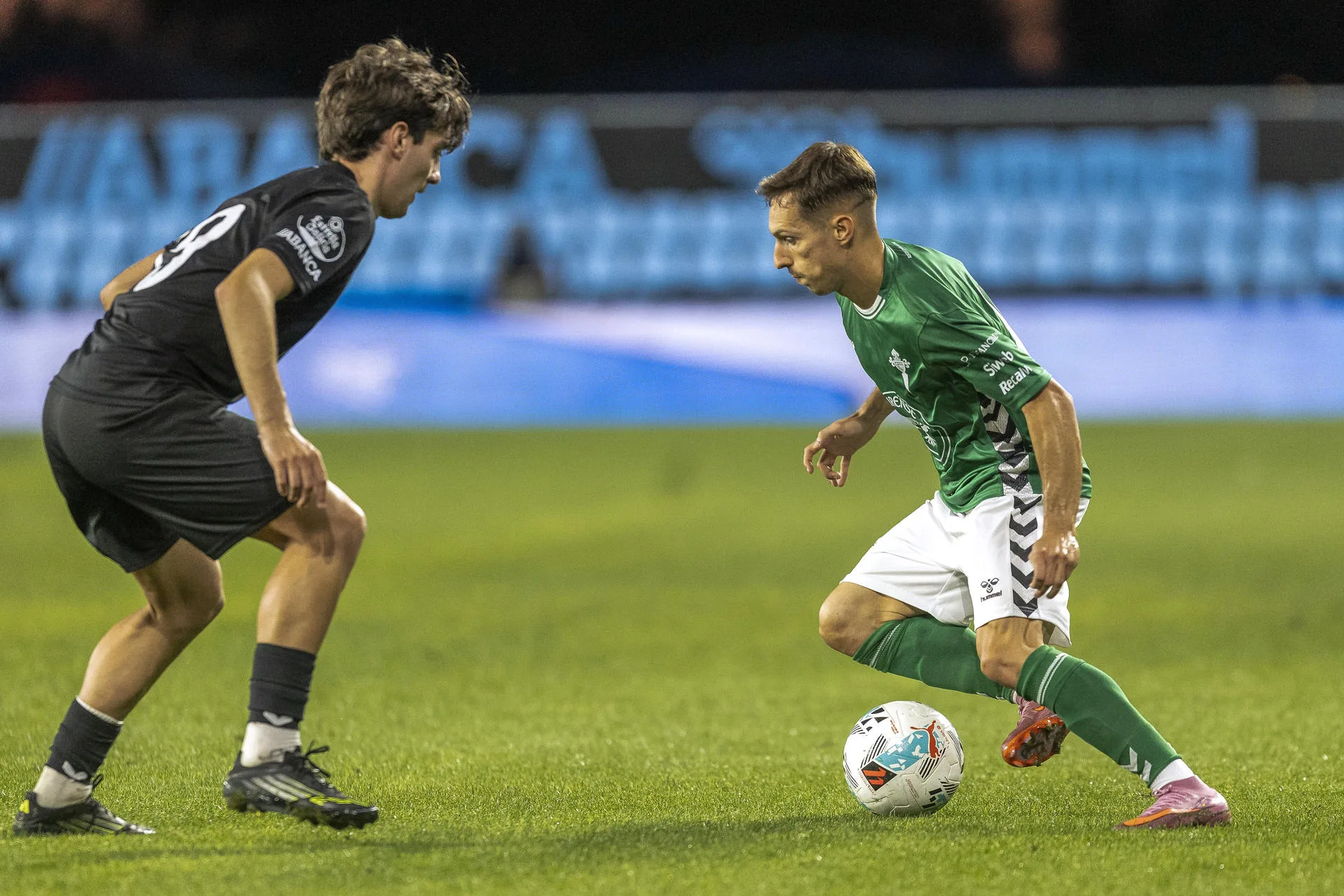 El jugador del Celta de Vigo Cervi (d) pugna por un balón con el jugador del Orense Samu en el partido de fútbol solidario 'Xuntos contra o lume' que Celta de Vigo y Orense jugaron este miércoles en el estadio de Balaídos, en Vigo. EFE/ Salvador Sas
