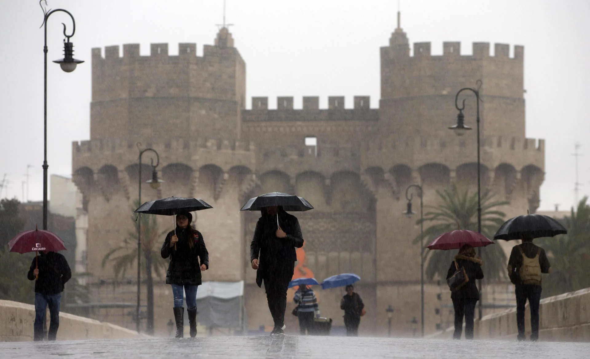 En la imagen de archivo, varias personas cruzan el puente de Serranos bajo la lluvia, en Valencia. EFE/Kai Försterling