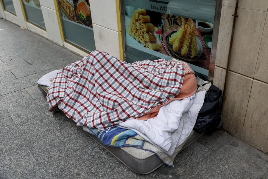 Un mendigo duerme sobre un colchón en una calle de Madrid.